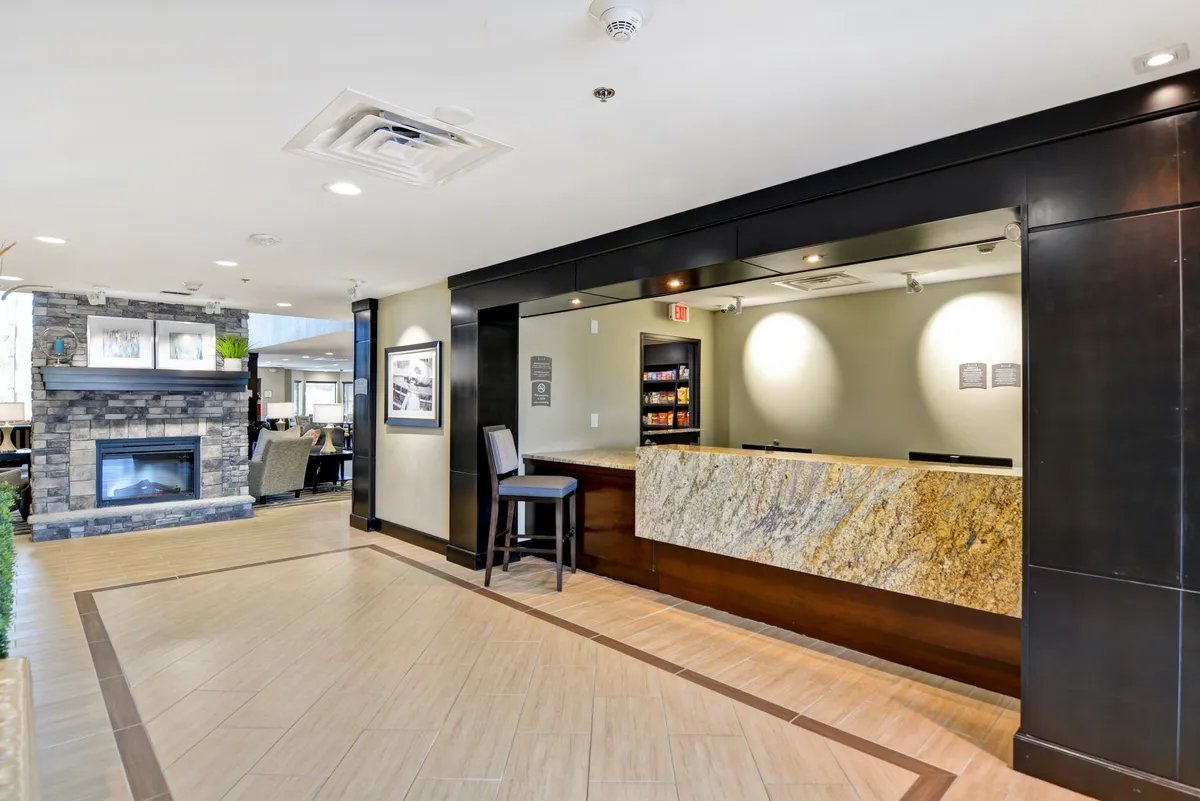 The image highlights the reception area with a cozy seating area and a prominent fireplace. Guests are seen checking in and relaxing, creating an inviting first impression that suggests a place where groups can easily gather and socialize before heading out or after returning from local adventures.