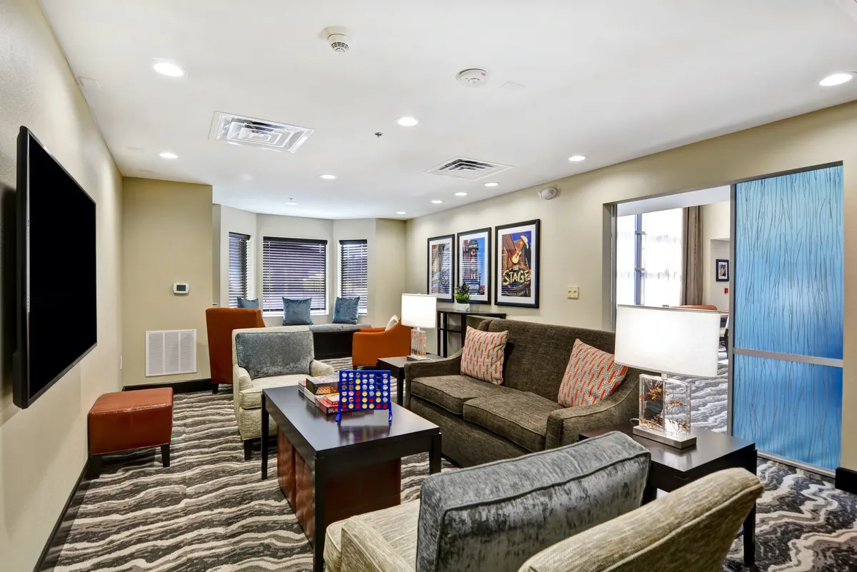 A welcoming living area featuring a comfortable sofa adorned with colorful cushions, a stylish coffee table with decorative items, a wall-mounted television perfect for entertainment, and framed art pieces adding personality to the space. The arrangement invites relaxation and social interaction, showcasing an open-plan flow ideal for gatherings.